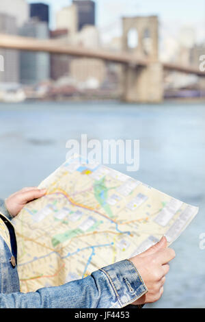 Weibliche Touristen Karte Fluss mit Brooklyn Bridge im Hintergrund halten Stockfoto