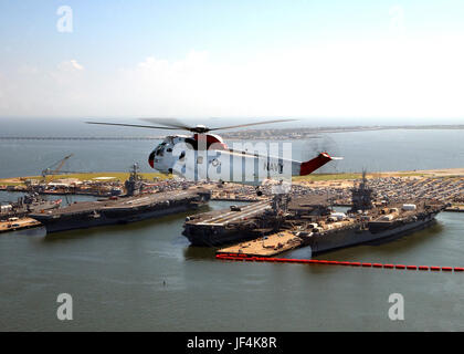 040827-N-4459K-002 ein UH - 3H Sea King Hubschrauber fliegt in der Nähe von drei Flugzeugträgern vertäut am Naval Station Norfolk, Virginia, am 27. August 2004.  (Von links nach rechts) Träger USS Harry S. Truman (CVN-75), USS George Washington (CVN-73) und USS Enterprise (CVN-65).  Die Helo erhält die Search and Rescue Unit am Naval Air Station Oceana, VA.  DoD-Foto von Petty Officer 1st Class Anthony M. Koch, US-Navy.  (Freigegeben) Stockfoto