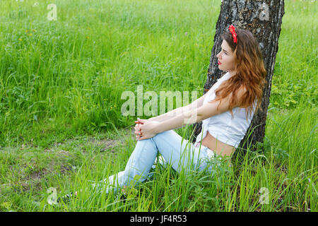 Mädchen sitzt auf einer Birke im herbstlichen Wald Stockfoto