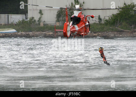 Kosten Sie Guard Rettungs-Schwimmer Sprünge aus HH-65 Dolphin Helikopter während einer Suche und retten Sie Demonstration von Staten Island Pier während der Fleet Week New York 27. Mai 2017 zu. Fleet Week New York feiert 29. Jahr 3700 Matrosen, Marines und Küste Gardisten von 10 Schiffen die Öffentlichkeit treffen. Foto: U.S. Coast Guard Petty Officer 2. Klasse Michael Himes Stockfoto