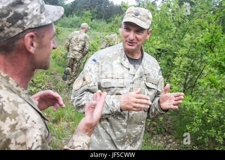 Ein Yavoriv GÜZ-Trainer bietet Feedback nach dem anhören ukrainischer Soldaten aus dem 1. Airmobile Bataillon, 79. Air Assault Brigade kurz ihren Plan zur Halbüberspülte Schützenpanzer während Fahrzeug Regenerationstraining am Yavoriv CTC International Peacekeeping und Security Center in der Nähe von Yavoriv, Ukraine, am 31. Mai zu erholen.    Yavoriv CTC-Personal zusammen mit Mentoren aus der US-Armee 45. Infantry Brigade Combat Team, führte die Ausbildung zum Soldaten von der 1-79. während der Rotation des Bataillons durch Yavoriv CTC. 45. ist in der Ukraine eingesetzt. Stockfoto