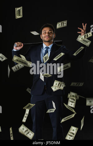 Zuversichtlich junger Geschäftsmann mit Baseball Schläger und Dollar-Banknoten fallen auf schwarz Stockfoto