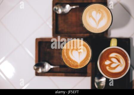 Baum Tassen Kaffee mit schönen Latte Kunst und Löffel auf Holzbrettern, auf weißem Hintergrund. Stockfoto