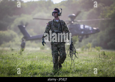 Ein Crew-Mitglied aus dem 1. Bataillon, 3. Angriff Regiment der US-Armee blickt auf als ein Apache Hubschrauber landet hinter ihm auf einem Truppenübungsplatz in der Nähe von Cincu Rumänien für edle springen 17 Übung am 3. Juni 2017. Stockfoto