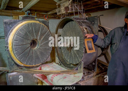 Hand mit einer alten Steinmühle Mühle gemacht, Mehl drinnen befindet sich in der Altstadt von Quito zu produzieren. Stockfoto