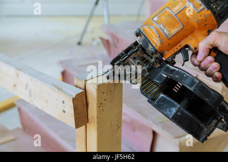 Bau der Waffe schießen die Nägel in die Holzwand Stockfoto