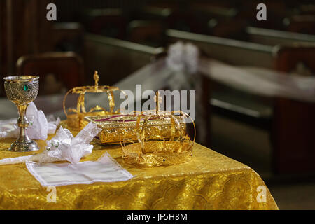 Kronen aus Gold für die Hochzeit auf dem Tisch in der Kirche. Stockfoto