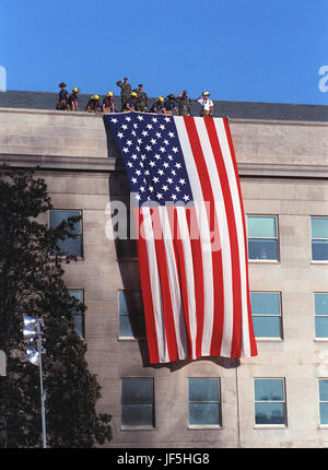 010912-D-9880W-085 Feuerwehrleute und Soldaten auf dem Dach des Pentagons entfalten eine große amerikanische Flagge während der 12. September 2001, Besuch von Präsident George W. Bush auf der Website von der vorherigen DayÕs vereitelte Anschlag auf das Pentagon.  Wie die Flagge über die Mauer, südlich von der Website drapiert wurde wo American Airlines Flug 77 das Gebäude beeinflusst begann die Katastrophe Arbeiter versammelten sich um den Präsidenten zu God Bless America zu singen.  DoD-Foto von R. D. Ward. Stockfoto