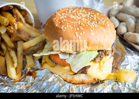 Ein Bacon Cheeseburger, Pommes Frites und Erdnüsse aus fünf Jungs Burger und Pommes, eine amerikanische fast-casual-Restaurant-Kette. Stockfoto