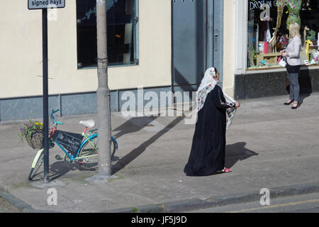 Asiatische Familie Flüchtling gekleidet Hijab Schal auf Straße in der UK alltägliche Szene Frau einkaufen Stockfoto