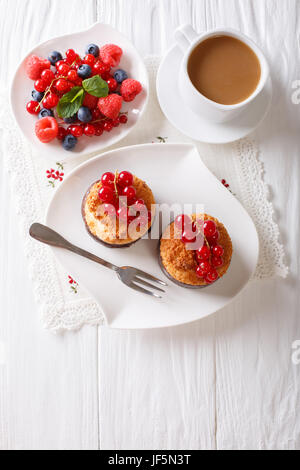 Kokos-Muffins mit Beeren und Kaffee mit Milch Nahaufnahme auf dem Tisch. vertikale Ansicht von oben Stockfoto