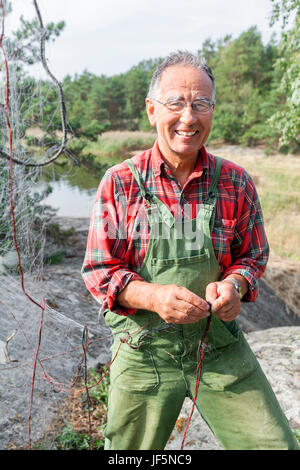 Lächelnder senior Mann Reparatur Fischernetz Stockfoto