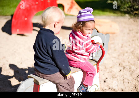 Mädchen und Jungen auf Spielplatz spielen Stockfoto