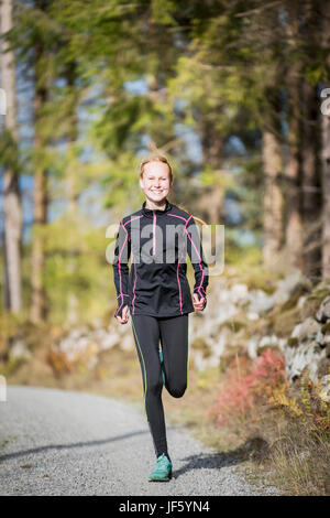 Junge Frau im Wald joggen Stockfoto