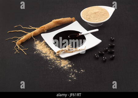 Gesunde Ginseng Ergänzungen. Frische Wurzel, Pillen, Extrakt und Pulver auf schwarzem Hintergrund. Stockfoto