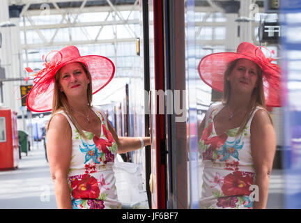 Eine Frau in einem roten Hut in London Waterloo besteigt einen Zug auf dem Weg zum Royal Ascot am Ladies Day Stockfoto