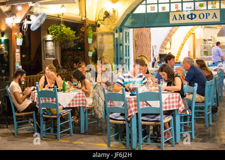 Menschen, die in einem traditionellen Restaurant (Taverne) am Ufer der Stadt Chania, Kreta, griechische Inseln, Griechenland essen Stockfoto