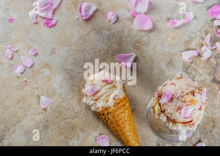 Sommer erfrischende Desserts. Vegane Ernährung essen. Eis mit Rosenblättern und Scheiben von Mandeln, klassische Waffel Eiswaffeln, auf eine Beige leichte Konz Stockfoto