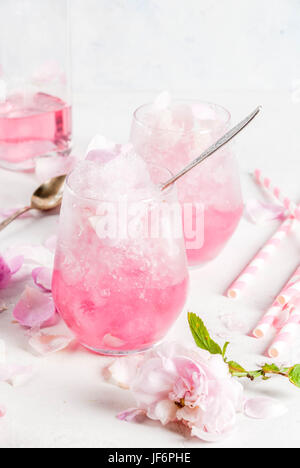 Sommer erfrischende Desserts. Vegane Ernährung essen. Eis, gefrorene rose, erstarrte und mit Rosenblättern und Roséwein. Auf einem weißen Betontisch mit Löffeln, str Stockfoto