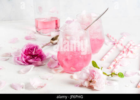 Sommer erfrischende Desserts. Vegane Ernährung essen. Eis, gefrorene rose, erstarrte und mit Rosenblättern und Roséwein. Auf einem weißen Betontisch mit Löffeln, str Stockfoto