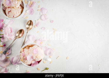 Sommer erfrischende Desserts. Vegane Ernährung essen. Eis mit Rosenblättern und Scheiben von Mandeln, weißen Schüsseln auf einem weißen Beton Tisch. Kopie Stockfoto
