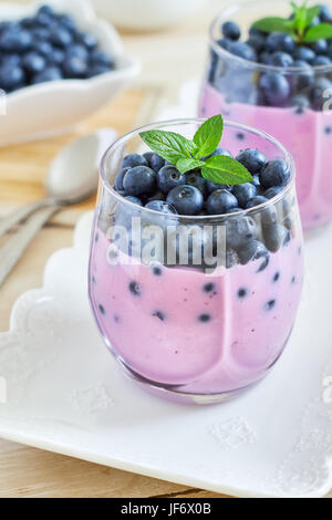 Heidelbeer Joghurt serviert mit frischen Blaubeeren und Minze Blätter Stockfoto