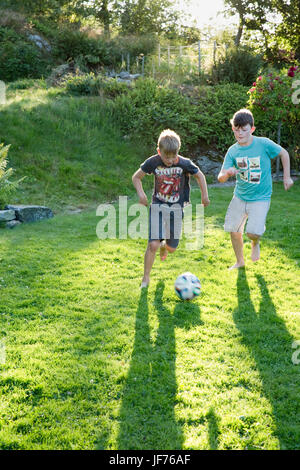 Jungs spielen Fußball im Garten Stockfoto