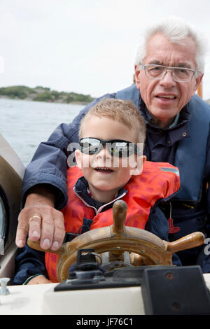 Junge fahren Boot mit Großvater Stockfoto