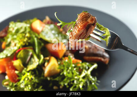 Gebackener Kürbis, Steak und Rucola auf einer Gabel Stockfoto