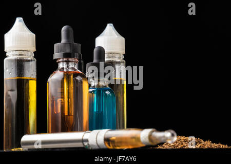 E-Liquid-Flaschen und e-Zigarette mit Haufen von gemahlenen Tabakblättern Stockfoto