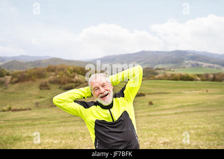 Aktive Senioren Läufer außerhalb auf grünen Hügeln, die Dehnung zu tun. Stockfoto