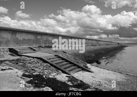 Schwarz / weiß Bild der Ufermauer und Schritte hinunter zum Strand auf Thorney Bay, Canvey Insel, Essex, England Stockfoto