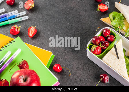 Zurück zur Schule. Ein herzhaftes gesundes Schulessen in einer Box: Sandwiches mit Gemüse und Käse, Beeren und Früchte (Äpfel) mit Notebooks, farbigen Stift Stockfoto