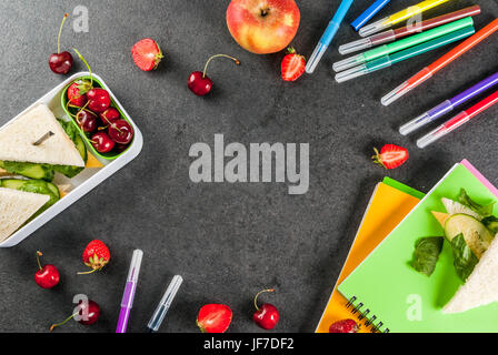 Zurück zur Schule. Ein herzhaftes gesundes Schulessen in einer Box: Sandwiches mit Gemüse und Käse, Beeren und Früchte (Äpfel) mit Notebooks, farbigen Stift Stockfoto