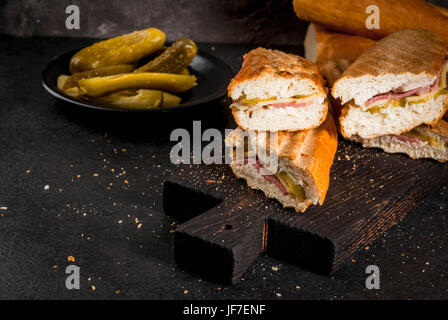 Traditionelle kubanische Küche, Snack, Party Essen. Cuban Sandwich von Baguette mit Schinken, Schweinefleisch, Käse, Gurken. Am schwarzen Tisch Textfreiraum Stockfoto