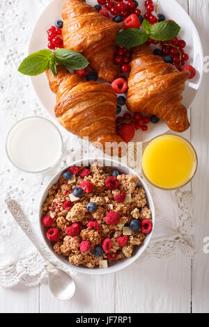 Müsli mit Beeren und Croissants, Milch und Orangensaft Nahaufnahme auf dem Tisch. vertikale Ansicht von oben Stockfoto