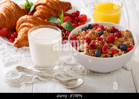 Hausgemachtem Müsli mit Beeren, Croissants, Milch und Saft Closeup auf dem Tisch. horizontale Stockfoto