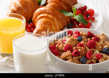 Leckeres Frühstück mit Müsli mit Beeren, sowie Croissants, Milch und Orangensaft Nahaufnahme auf dem Tisch. horizontale Stockfoto