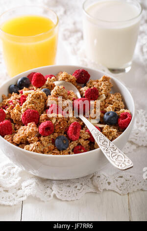 Gebackene Müsli mit getrockneten Himbeeren und Heidelbeeren, Milch und Saft Nahaufnahme auf einem Tisch. vertikale Stockfoto