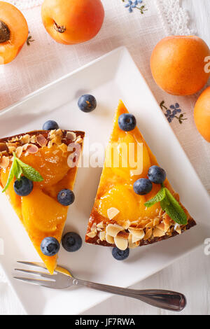 Aprikosen-Kuchen mit Heidelbeeren, Minze und Muttern Nahaufnahme auf einer Platte. vertikale Ansicht von oben Stockfoto