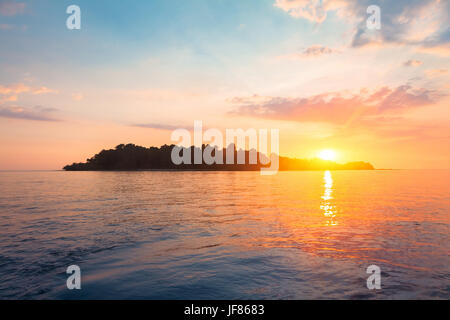 Silhouette einer tropischen Insel vom Meer Wasser umgeben am Horizont mit einem wunderschönen Sonnenuntergang Licht Stockfoto