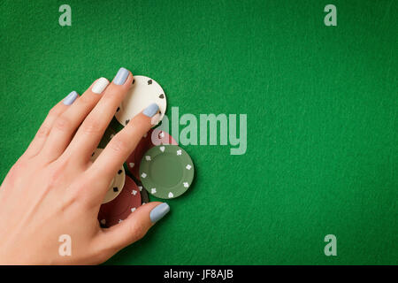 Frau Hand mit Poker-Chips auf grüne Casino Filz Hintergrund. Glücksspiel Thema Bild mit Textfreiraum Stockfoto