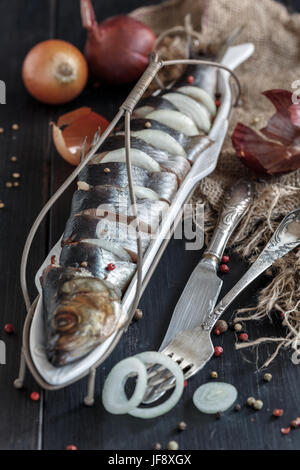 Gesalzene Heringe mit Zwiebeln und Gewürzen. Stockfoto