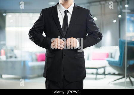 Intelligente Geschäftsmann im schwarzen Anzug mit Schaltfläche "Pose". Stockfoto