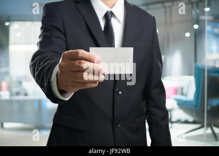 Intelligente Geschäftsmann im schwarzen Anzug mit zeigen die Namen Karte Pose. Stockfoto