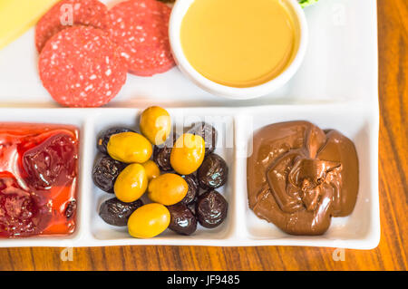 Nahaufnahme von traditionelles türkisches Frühstück serviert in einem Porzellanteller mit Olivenöl, Marmelade, Wurst, Käse, Nutella und Sesam-paste Stockfoto