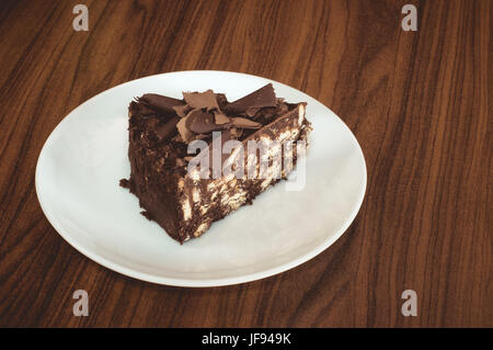 Köstliche Mosaik-Schoko-Biskuit-Torte serviert in einem weißen Teller auf einem Holztisch Stockfoto