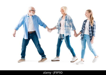 glückliche Großvater, Großmutter und Enkelin zu Fuß und Hand in Hand zusammen isoliert auf weiss Stockfoto