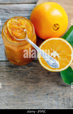 Teelöffel in ein Glas mit Orange Marmelade. Stockfoto