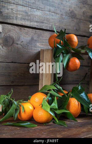 Mandarinen mit Blättern auf hölzernen Kasten Stockfoto